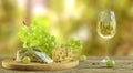 White wine, cheese and grapes on wooden table with blurred wineyard in background