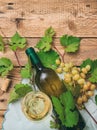 White wine glass and bottle and fresh grapes on wooden background Royalty Free Stock Photo