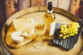 White wine in glass, bottle with grape and cheese on barrel front wood wall background. Royalty Free Stock Photo