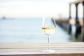 white wine glass with coastal ocean pier in the background