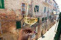 White wine glass in hand of italian person, living in historical Siena city, Tuscany. Leisure in Italy