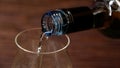 White wine is poured into glass in front of a wooden background Royalty Free Stock Photo