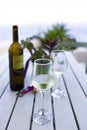 White wine served on a cold wineglass with another glass and a bottle on a wooden table