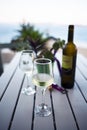 White wine served on a cold wineglass with another glass and a bottle on a wooden table Royalty Free Stock Photo