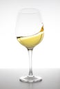 White wine swirling in glass on white background