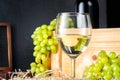 White wineglass and white yellow green bunches of berry grapes with bottle of wine