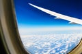White wing of the aircraft view from airplane window seat flying in the blue sky with white clouds background Royalty Free Stock Photo