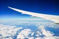 White wing of the aircraft view from airplane window seat flying in the blue sky with white clouds background Royalty Free Stock Photo