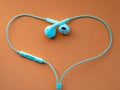 White wired headphones, headset in the shape of the heart on an orange background.