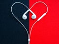 White wired headphones, heart-shaped headset on a black-red background. Royalty Free Stock Photo