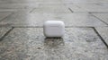 white wireless earbud case resting outdoor pavement surface Royalty Free Stock Photo