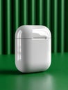 White wireless earbuds case on green textured surface. Royalty Free Stock Photo