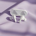White wireless earbuds with a charging case on a light purple surface Royalty Free Stock Photo