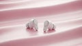 White wireless earbuds are displayed on a pink silky surface Royalty Free Stock Photo