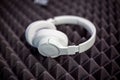 White wireless overhead monitor headphones lie on a dark foam rubber noise canceling panel. close-up soft focus, blur