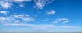 Scattered white clouds float in rich blue sky panorama