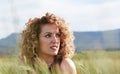 white woman in black dress with gold detail, curly hair, looking at the horizon