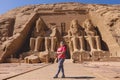 White Woman Tourist in front of the Colossal Statues of Ramesses II seated on throne near the entrance to Great Temple Abu Simbel Royalty Free Stock Photo