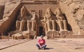 White Woman Tourist in front of the Colossal Statues of Ramesses II seated on throne near the entrance to Great Temple Abu Simbel Royalty Free Stock Photo