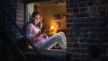 White Woman Using a Smartphone while Sitting on a Windowsill in Brooklyn Style Brownstone House Royalty Free Stock Photo