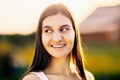 Portrait of Caucasian brunette female in her 20s , in light of setting sun against blurred background of rural landscape