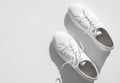 White women's leather sneakers with sun shadows on white background top view. Stylish youth sneakers, sports shoes Royalty Free Stock Photo