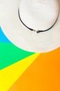 White women`s straw beach hat on rainbow multicolored pinwheel striped sunburst background. Summer vacation fashion