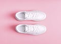 White womens gumshoes on a pink background.