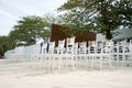 A group of white chiavari chairs on the beach wedding preparation, cones of roses petals - front side, low angle view