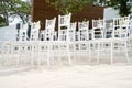 A group of white chiavari chairs on the beach wedding preparation, cones of roses petals - front side, low angle view