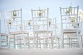 A group of white chiavari chairs on the beach wedding preparation, cones of roses petals - back, low angle view