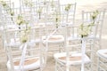 A group of white chiavari chairs on the beach wedding preparation, cones of roses petals - back, top view