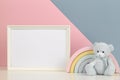 White blank frame with teddy bear and pastel toy rainbow on white deskand light pink and blue background Royalty Free Stock Photo