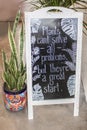White wood standing sign surrounded by plants saying plants can`t solve all problems but they are a great start