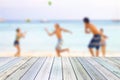 White wood table on blurred young tourists playing ball on beach Royalty Free Stock Photo