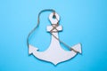 White wooden anchor figure on light blue background, top view