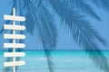 White wooden arrow signpost over blue ocean palm landscape Royalty Free Stock Photo