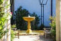 A white wooden awning in the garden covered with lush green plants and colorful flowers with stone pillars and a water fountain Royalty Free Stock Photo