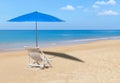 White wooden beach chair and blue parasol on tropical beach Royalty Free Stock Photo
