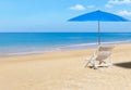 White wooden beach chair and blue parasol on tropical beach Royalty Free Stock Photo
