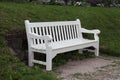 White wooden bench in the park on the background of a green lawn front view Royalty Free Stock Photo