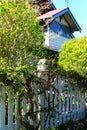 White wooden bird house on a picket fence post Royalty Free Stock Photo