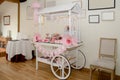 White wooden candy cart decorated with white and pink candy and decorations.