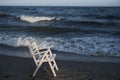 White wooden chair on the beach. Empty beach, sunset, cold weather and the sea.