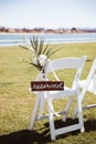 White wooden chair with rustic Reserved sign on green lawn . Outdoor wedding ceremony Royalty Free Stock Photo