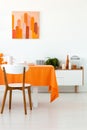 White wooden chair at table with orange cloth in dining room