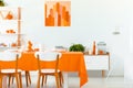 White wooden chairs at table in orange dining room interior with poster Royalty Free Stock Photo
