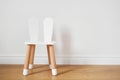 White and wooden child chair with rabbit ears. White wall copy space