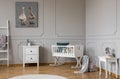 White wooden cradle with emerald pillow and toys in the corner of stylish scandinavian baby bedroom interior, real photo with copy Royalty Free Stock Photo