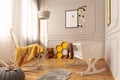 White cradle and rocking chair with cozy yellow blanket in bright grey toddler room